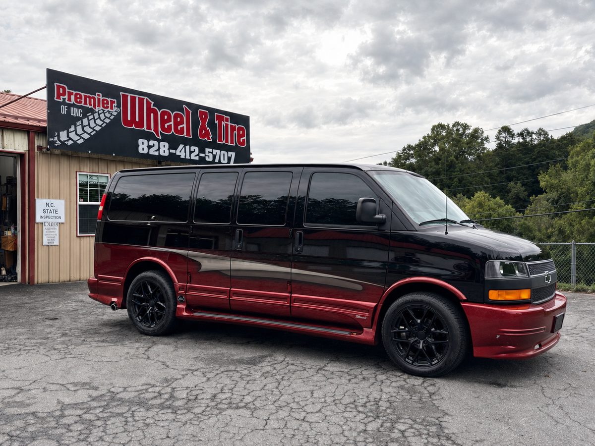 Black and red Chevy Express conversion van on gloss black wheels outside our Asheville shop